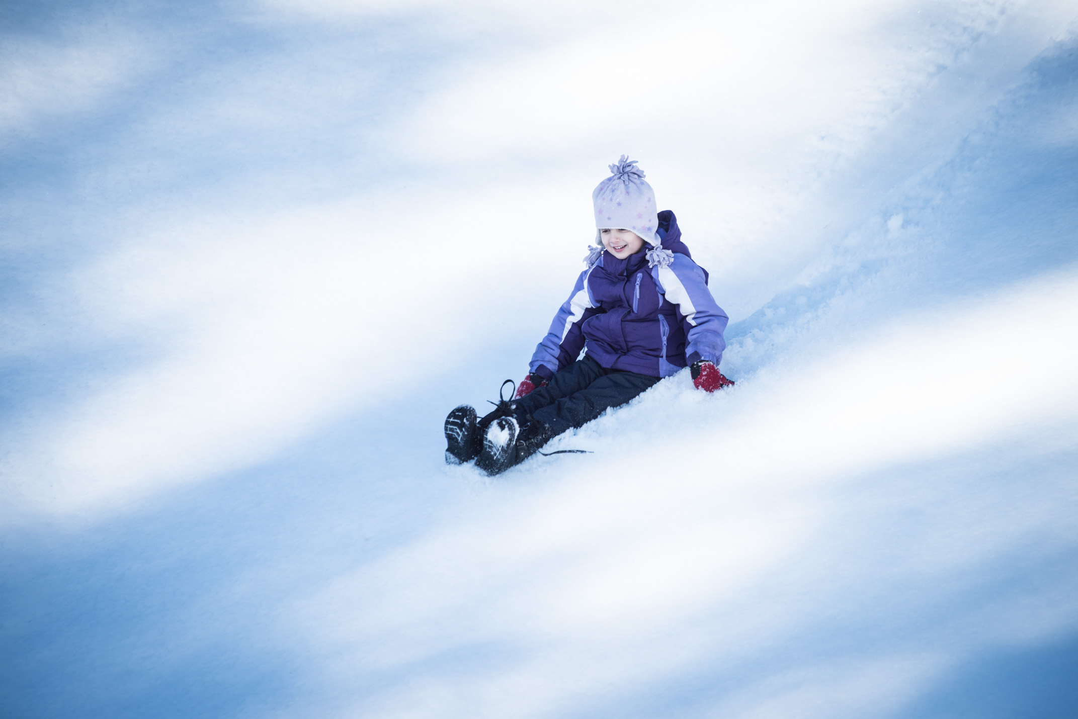 A little girl slides down a snowy hill in Plymouth, Massachusetts.