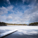 A bright blue winter sky hangs over a frozen pond in Plymouth.